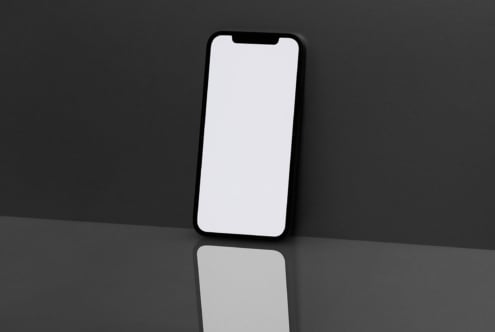 Smartphone mockup with blank screen against dark background reflecting on glossy surface. Ideal for showcasing mobile app designs and branding concepts.