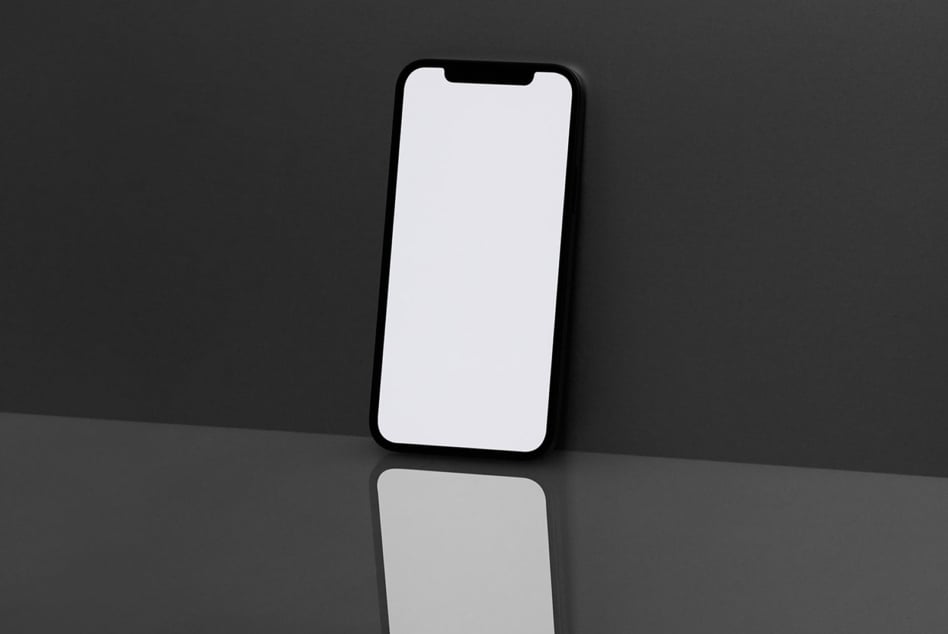 Black iPhone with blank white screen against dark gray backdrop, clean reflection below
