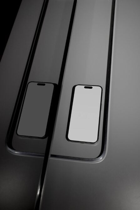 Two iPhones stacked on dark striped background with blank screens