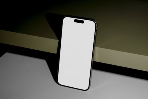 Smartphone mockup with blank screen on a minimalistic green and gray surface perfect for showcasing app designs and modern user interfaces to designers.