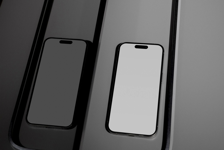 Flat lay of two iPhones on geometric dark stripes with empty displays