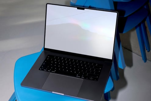 Laptop mockup on a blue chair with blank screen for design projects. Perfect for showcasing digital assets like graphics. Ideal for designers.