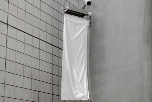 White vertical flag mockup on a modern tiled wall background perfect for designers seeking realistic graphics for outdoor advertisements and branding.