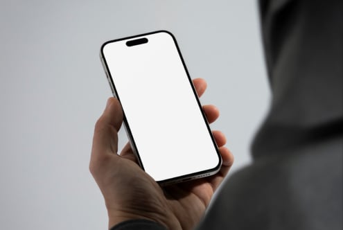 Mockup of a smartphone held in hand with a blank white screen ideal for app design presentations and digital product showcases. Perfect for designers.