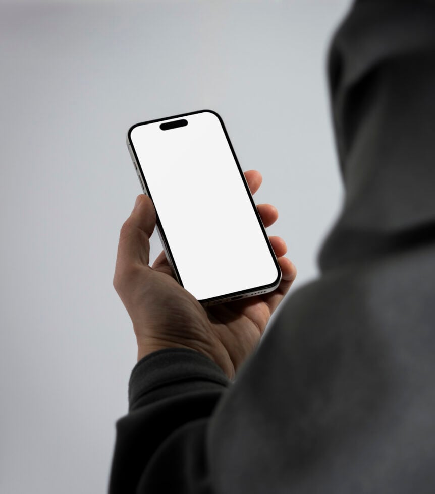 Person holding smartphone with blank screen. Mobile phone mockup suitable for apps UI UX design presentations. Modern tech device in hand close-up.