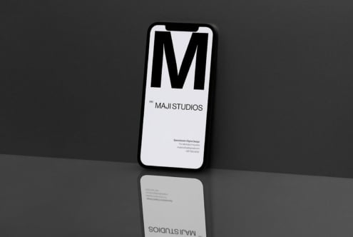 Smartphone mockup with Maji Studios branding on screen, minimalist design, reflection on glossy surface, perfect for showcasing digital products