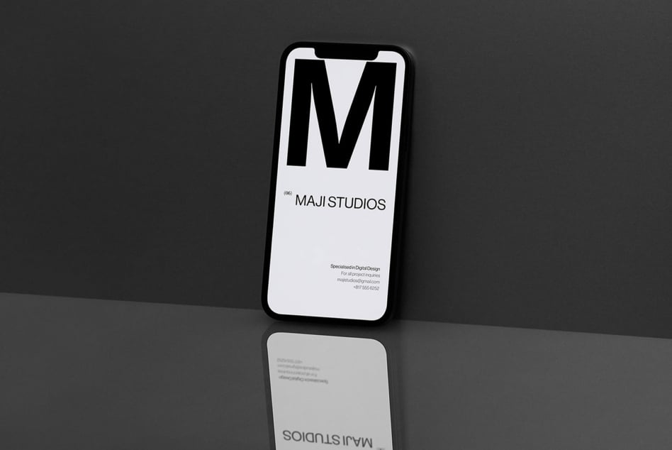 Black iPhone displaying Maji Studios logo in white on light background with contact info