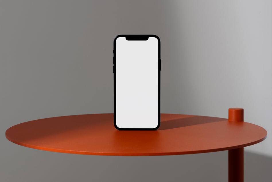 Mobile phone mockup centered on orange round table with blank white screen