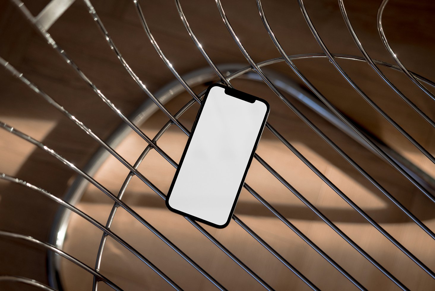 Smartphone mockup with blank screen on a metal chair background suitable for designers in digital assets marketplace featuring templates and graphics.