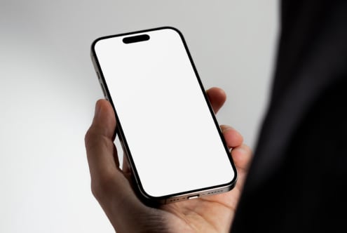 Person holding smartphone with blank screen mockup for designers. Ideal for showcasing app designs or templates. High-quality mobile display mockup.