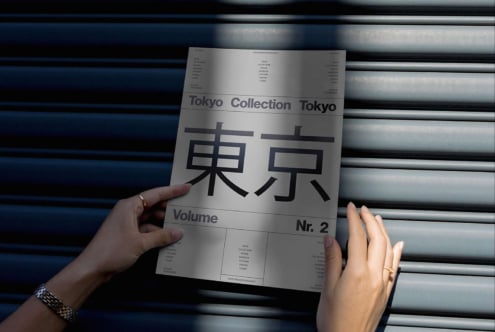 Hands holding a poster with Tokyo text in a shadowed setting ideal for mockups templates or graphics showcasing urban design and modern typography.