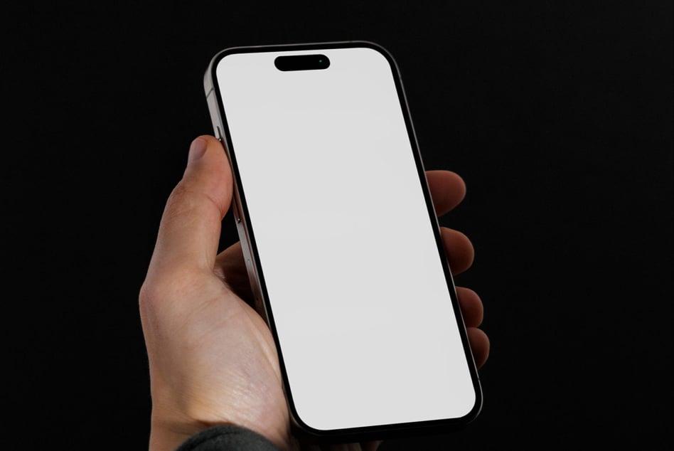 Hand holding phone with blank white screen against black background
