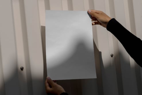 Person holding blank paper in front of corrugated metal background perfect for mockup design projects presentations branding minimalist template
