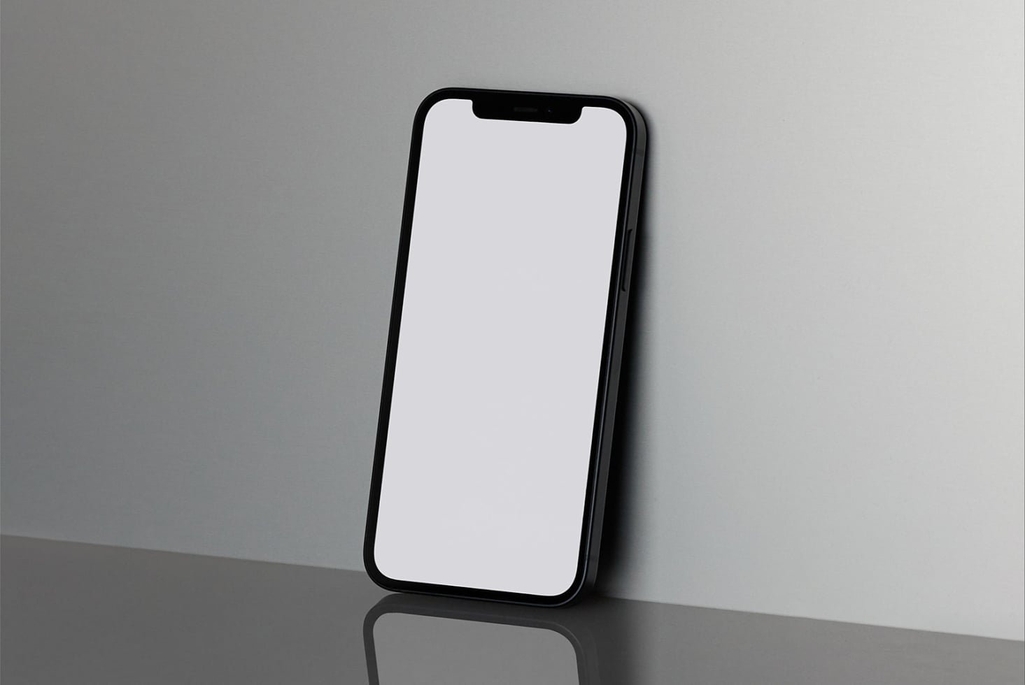 Black iPhone standing upright on minimal gray surface with clean white screen