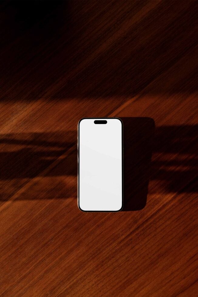 Smartphone mockup on a wooden surface with soft shadows. Ideal for showcasing UI UX design templates device graphics and mobile app presentations.
