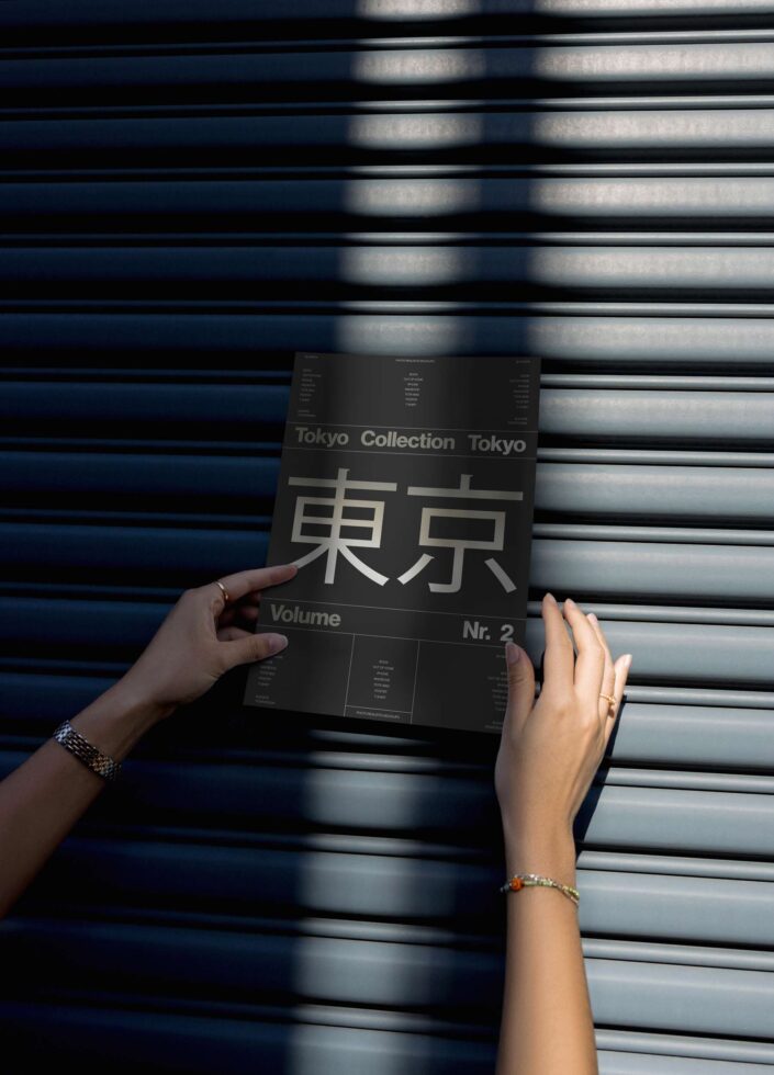 Hands holding a Tokyo Collection mockup poster against a metal shutter background. Ideal for designers, fonts, graphics, templates, creative assets.