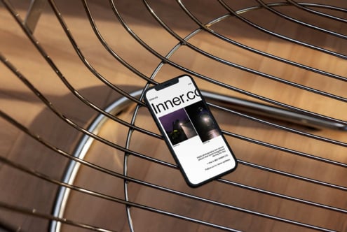 Smartphone on modern wire chair displaying a website with photography content suitable for digital assets mockups designers tech UI smartphone SEO