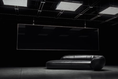 Modern black leather sofa in a minimal studio setting with geometric ceiling lights design mockup for interiors furniture designers SEO optimized