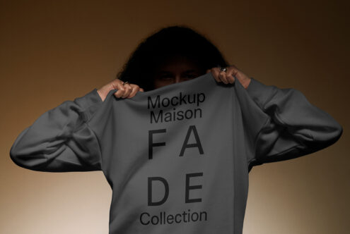 Mockup of a person holding a grey sweatshirt showing text Mockup Maison FADE Collection. Ideal for designers seeking apparel mockup assets.