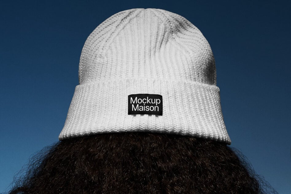 Cream ribbed beanie with black label patch visible against blue background