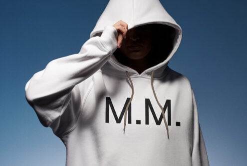 Hoodie mockup featuring a person in a white sweatshirt with bold M M letters, ideal for showcasing logo designs. Perfect for apparel branding projects.