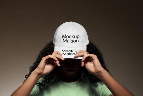 White baseball cap mockup with bold text held by a person in a dark setting perfect for designers seeking customizable hat templates and fashion graphics.