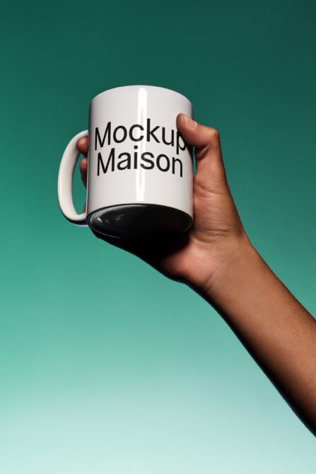 White mug with black text held in hand against teal background