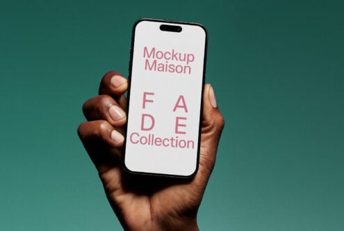 Hand holds smartphone displaying Mockup Maison FADE Collection against green background. Ideal for showcasing mobile designs in digital mockup templates.