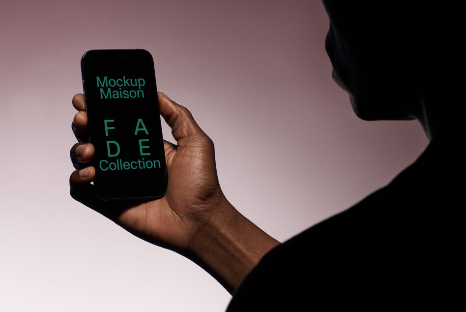Hand holding smartphone mockup with teal text on black screen against pink background