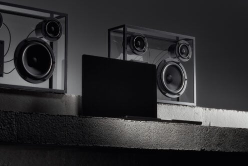 Dark laptop mockup with minimalist glass speakers on a concrete surface ideal for tech product showcases sleek design style keywords: Mockups Templates Graphics
