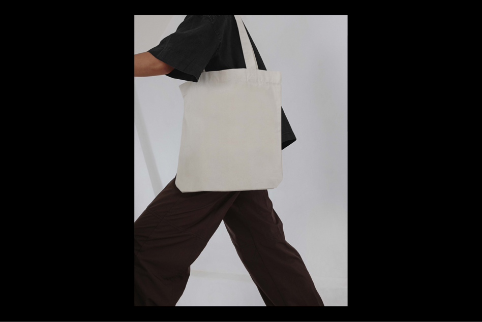 Tote bag mockup featuring a person holding a blank canvas bag. Ideal for showcasing branding designs. Perfect for graphic designers and product templates.