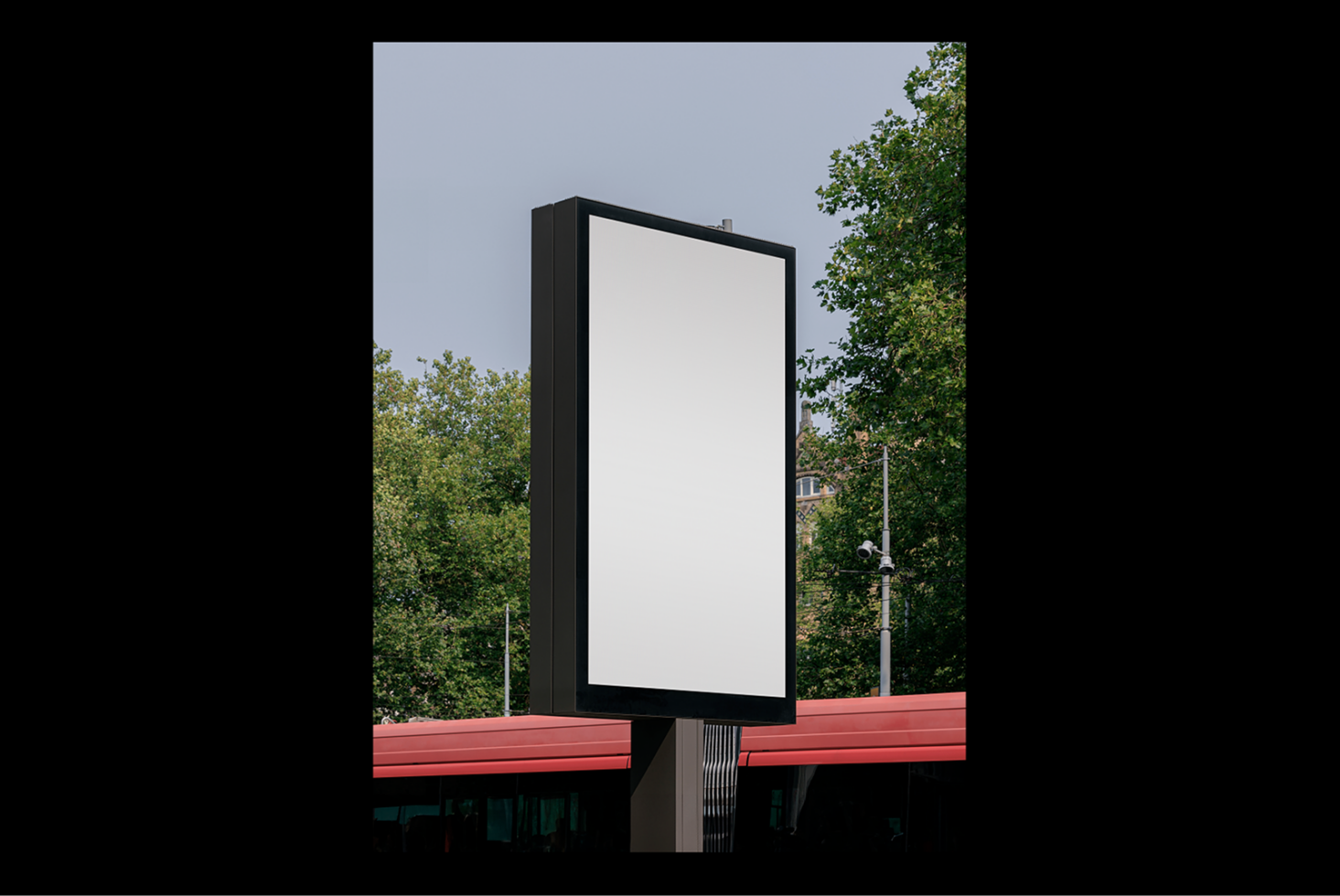 Blank vertical billboard mockup in urban setting surrounded by trees ideal for showcasing advertising designs and graphic templates for designers.