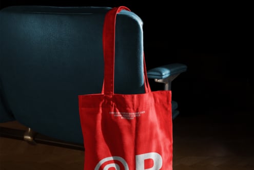 Red tote bag mockup hanging on a blue chair. Ideal for showcasing branding designs. Perfect for designers in need of modern and stylish mockups.