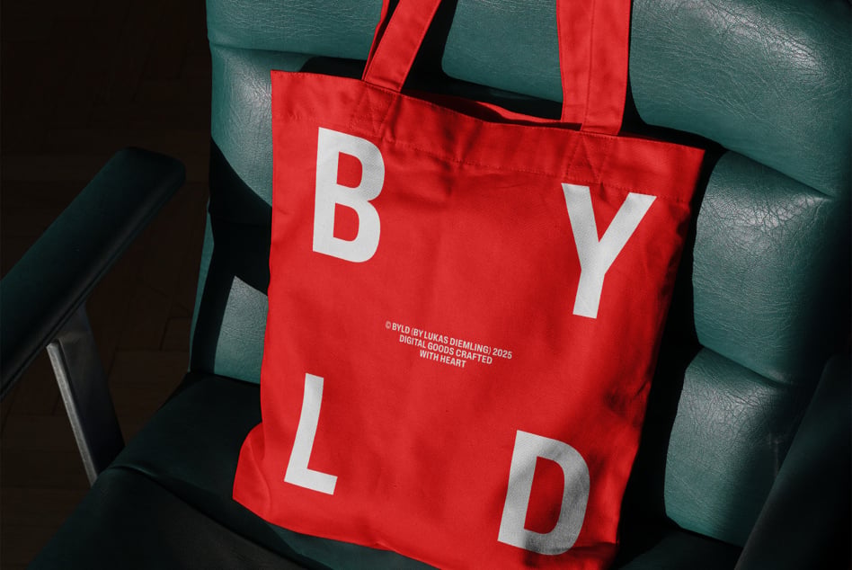 Red tote spelling BYLD in white letters draped on teal leather seat