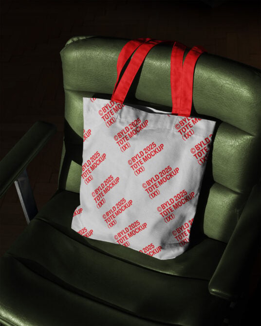 White tote featuring red repeating text mockup on olive chair back