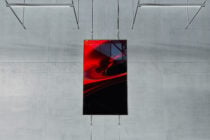 Red abstract art poster hanging from chains against concrete wall