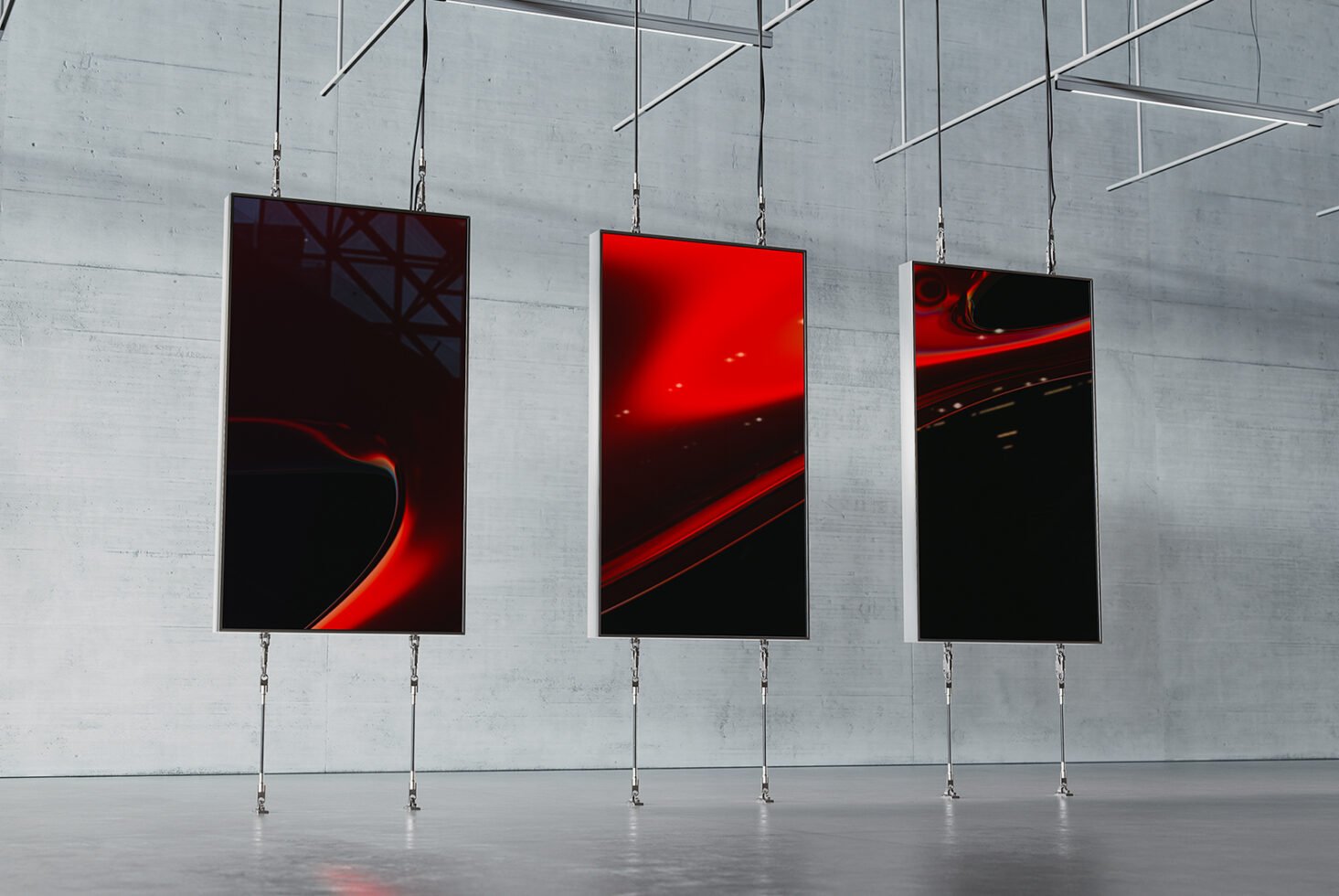 Three modern digital art frames with abstract red and black designs hang in an industrial space. Ideal for showcasing in graphic design mockups.