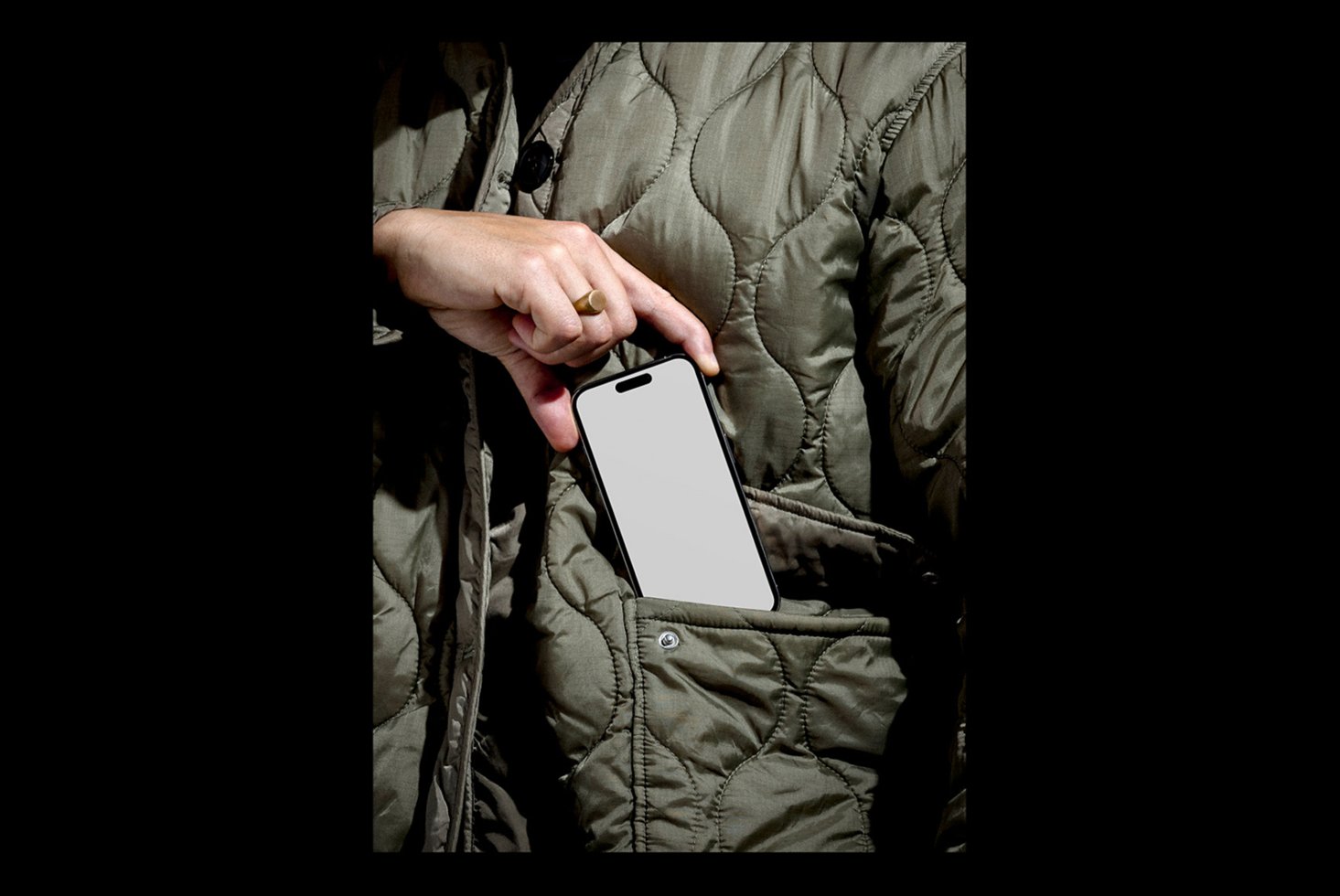 Mockup of hand holding smartphone with blank screen against quilted jacket background. Ideal for showcasing mobile app designs or user interface templates.