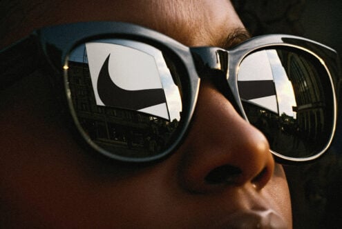 Close-up of sunglasses reflecting an urban scene with a bold logo silhouette. Ideal for use in design mockups, templates, and graphic projects.