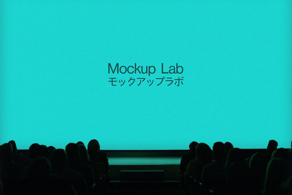Theater audience watching bright turquoise screen displaying Mockup Lab text