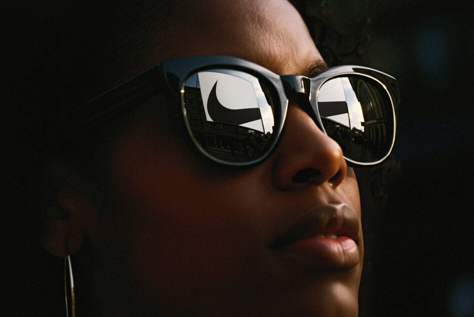 Close-up portrait of person wearing sunglasses reflecting cityscape and branding, perfect for designers seeking trendy urban mockup graphics.