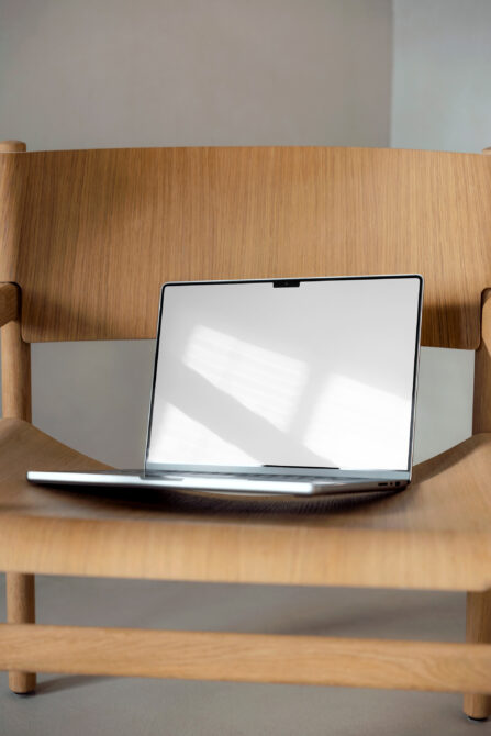 Silver laptop on wooden shelf between support arms with bright screen
