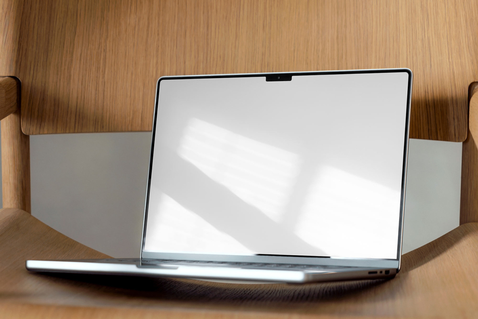 Laptop on wood shelving unit showing blank white screen with natural shadows