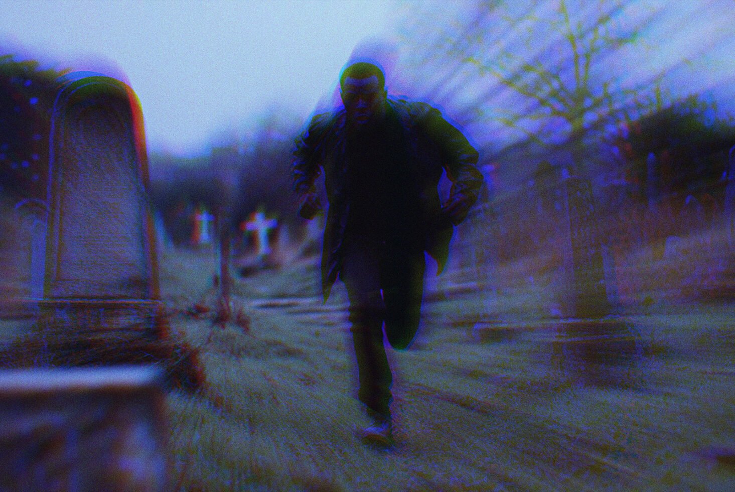 Man running through a misty graveyard with a dynamic blurred effect and dark tones, perfect for horror graphics or thriller movie posters.