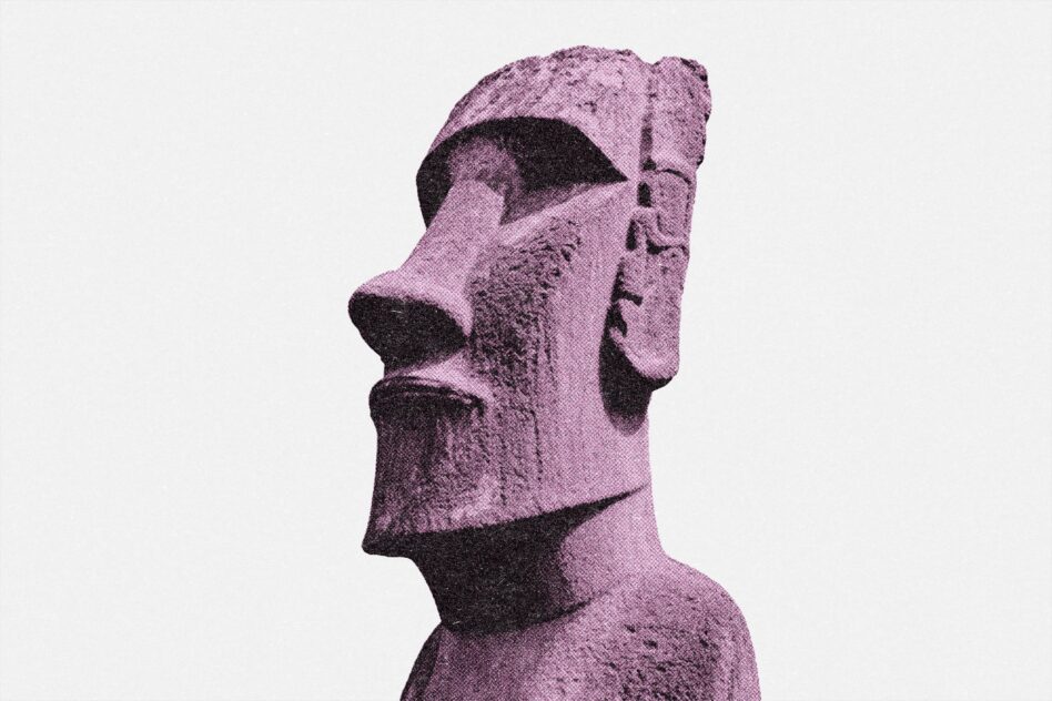 Stone moai sculpture with textured purple finish against light neutral background