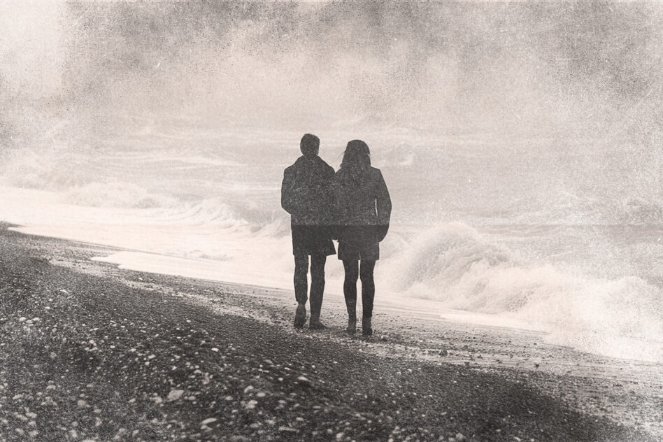Black silhouettes of couple on grainy beach landscape photo