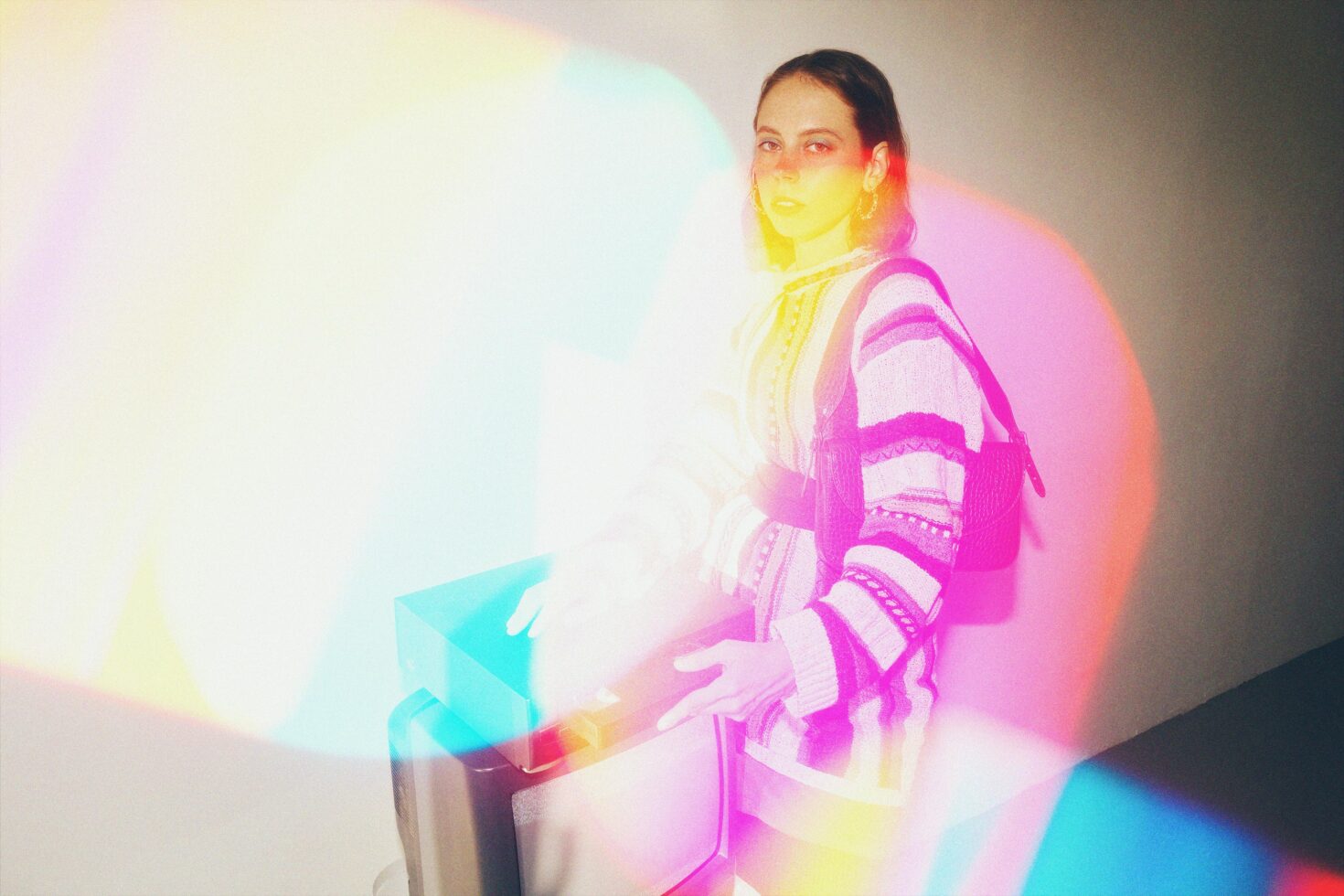 Designer working with a vibrant holographic light effect on a TV screen creating a colorful atmosphere. Ideal for graphic design and template inspiration.