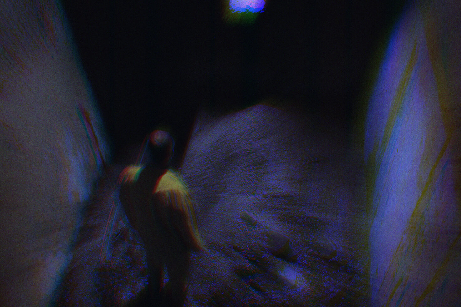 Blurry surreal image of a lone figure in a dark tunnel with colorful reflections perfect for design inspiration in abstract or urban-themed digital graphics.