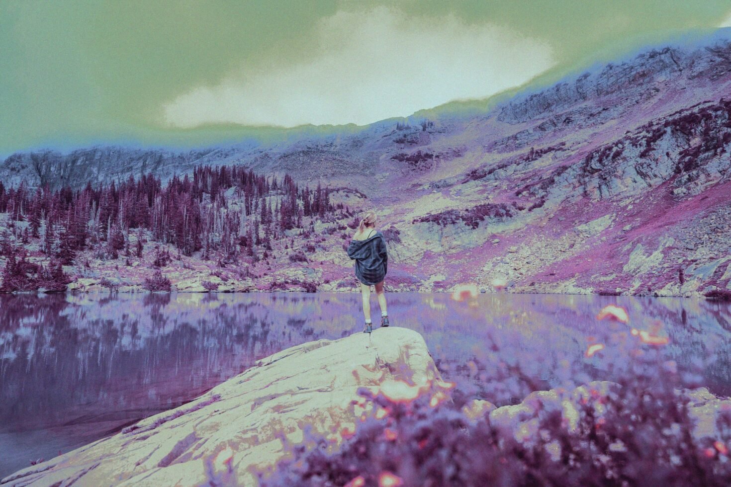 Surreal mountain landscape with a reflective lake and person standing on a rock. Graphic design, photo editing, fantasy scene, digital art background.