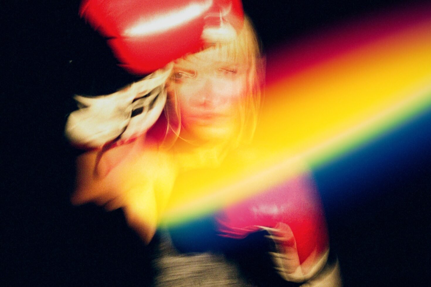 Blurred motion image of a female boxer with red gloves and a vibrant rainbow light effect on black. Perfect for creative graphic design projects.